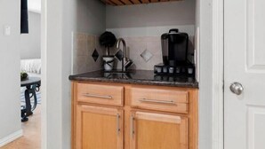 A compact kitchen with wooden cabinets, a countertop, and a coffee maker. - World Cup Ready 2BR Near NRG Stadium Skip the Parking (Houston)