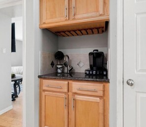 A compact kitchen with wooden cabinets, a countertop, and a coffee maker. - World Cup Ready 2BR Near NRG Stadium Skip the Parking (Houston)