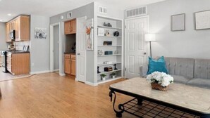 A modern kitchen with wooden cabinets, a dining area with a table, and a living room with a sofa and decorative pillows. - World Cup Ready 2BR Near NRG Stadium Skip the Parking (Houston)