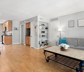A modern kitchen with wooden cabinets, a dining area with a table, and a living room with a sofa and decorative pillows. - World Cup Ready 2BR Near NRG Stadium Skip the Parking (Houston)
