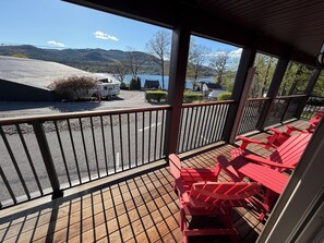 A covered outdoor area with red chairs and a view of a lake and mountains.