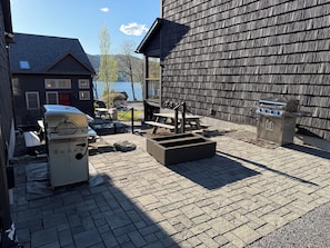 Un patio con una parrilla, asientos al aire libre y vista a un cuerpo de agua.