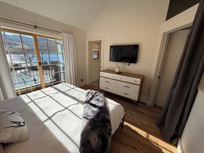 Habitació amb un llit, televisió, taulell i finestra que ofereix vista d'una massa d'aigua.