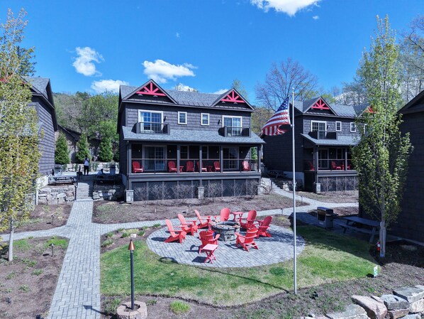 A two-story building with a covered patio area featuring red chairs and a fire pit.
