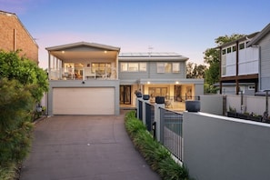 A two-story residential building with a garage, a balcony, and a covered outdoor seating area.