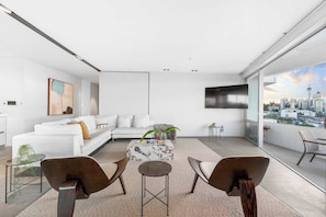 Ein modernes Wohnzimmer mit einem weißen Sofa, einem Couchtisch und zwei Sesseln.