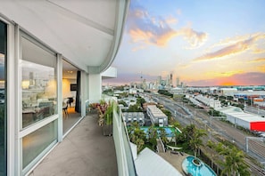 Ein Balkon mit Blick auf die Stadt, ein Pool und eine moderne Gebäudefassade.