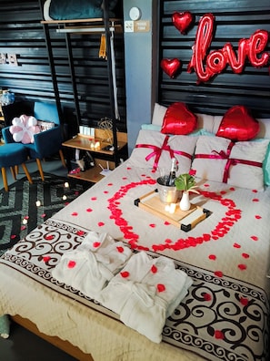 A bed with rose petals, a heart-shaped decoration, and a 'love' sign. - Vrbo Property (Paty do Alferes)