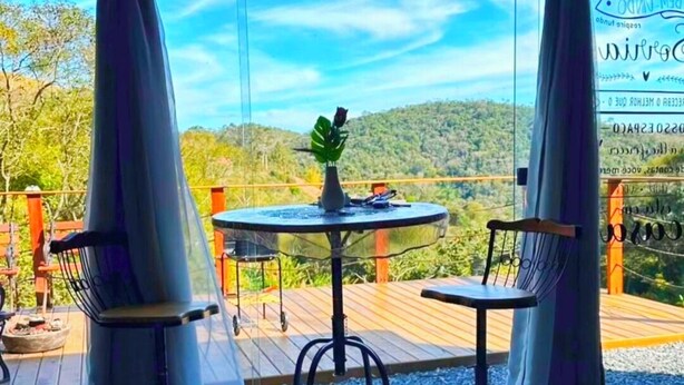 Ein Bett mit Blick auf eine Terrasse, ein Tisch mit Stühlen und eine Pflanze in einer Vase.