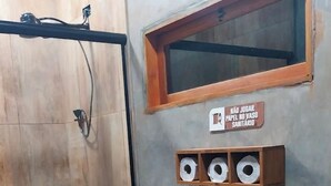 Ein Badezimmer mit Dusche, Toilette und Ablage für Toilettenpapier.