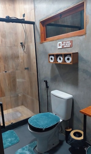A bathroom with a shower, toilet, and a shelf with toilet paper.
