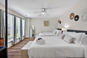 Une chambre d’hôtel avec deux lits, un ventilateur de plafond, un grand miroir et une vue sur l’extérieur.