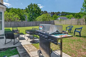Un jardin avec un barbecue mobile, du mobilier d’extérieur et une clôture en bois.