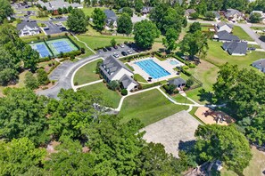 Vue aérienne d’un quartier résidentiel avec des maisons, un court de tennis et une piscine.