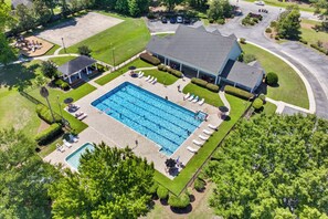 Vue aérienne d’une propriété résidentielle dotée d’une grande piscine rectangulaire, d’un patio couvert et d’une pelouse bien entretenue.