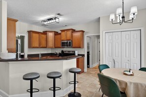 A kitchen with wooden cabinets, a stainless steel microwave, a sink, and a bar stool area. - Savannah Oasis: Huge 6BR Home w/Arcade & King Beds
Sleep 12, 9 beds, 6 BR, 3 BA (Pooler)