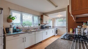 Una cucina moderna con mobili bianchi, un piano di lavoro in granito, forno integrato e una finestra con persiane.