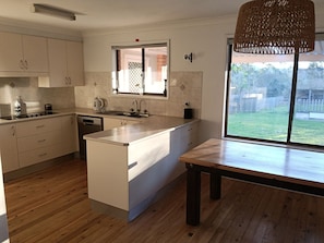 A kitchen with a wooden table, a window, and a hanging light fixture.