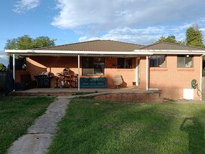 Una casa a un piano con veranda coperta, barbecue e divano blu.
