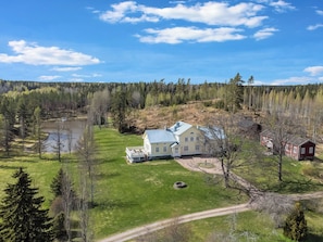 A large house with a metal roof, surrounded by a pond, trees, and a dirt path. - Vanhakylä gård väentupa by Interhome (Sastamala)