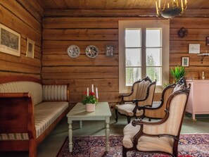 A log cabin interior with a sofa, two chairs, a table with a plant, and a window. - Vanhakylä gård väentupa by Interhome (Sastamala)