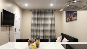 A modern living room with a marble table, a flat-screen TV, a sofa, and a cityscape painting. - NEW 2B Duplex near Sport Complex & Airport Unit-A (Philadelphia)
