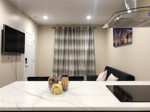 Una sala de estar moderna con una mesa de mármol, un televisor de pantalla plana, un sofá y una pintura de un paisaje urbano.