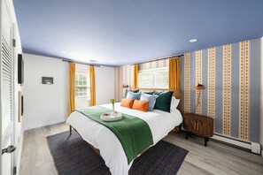 Une chambre à coucher avec un lit, une table de chevet, une lampe et une fenêtre avec des rideaux.
