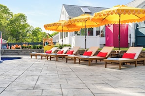 Un espace aménagé au bord de la piscine, avec des chaises longues et des parasols jaunes.