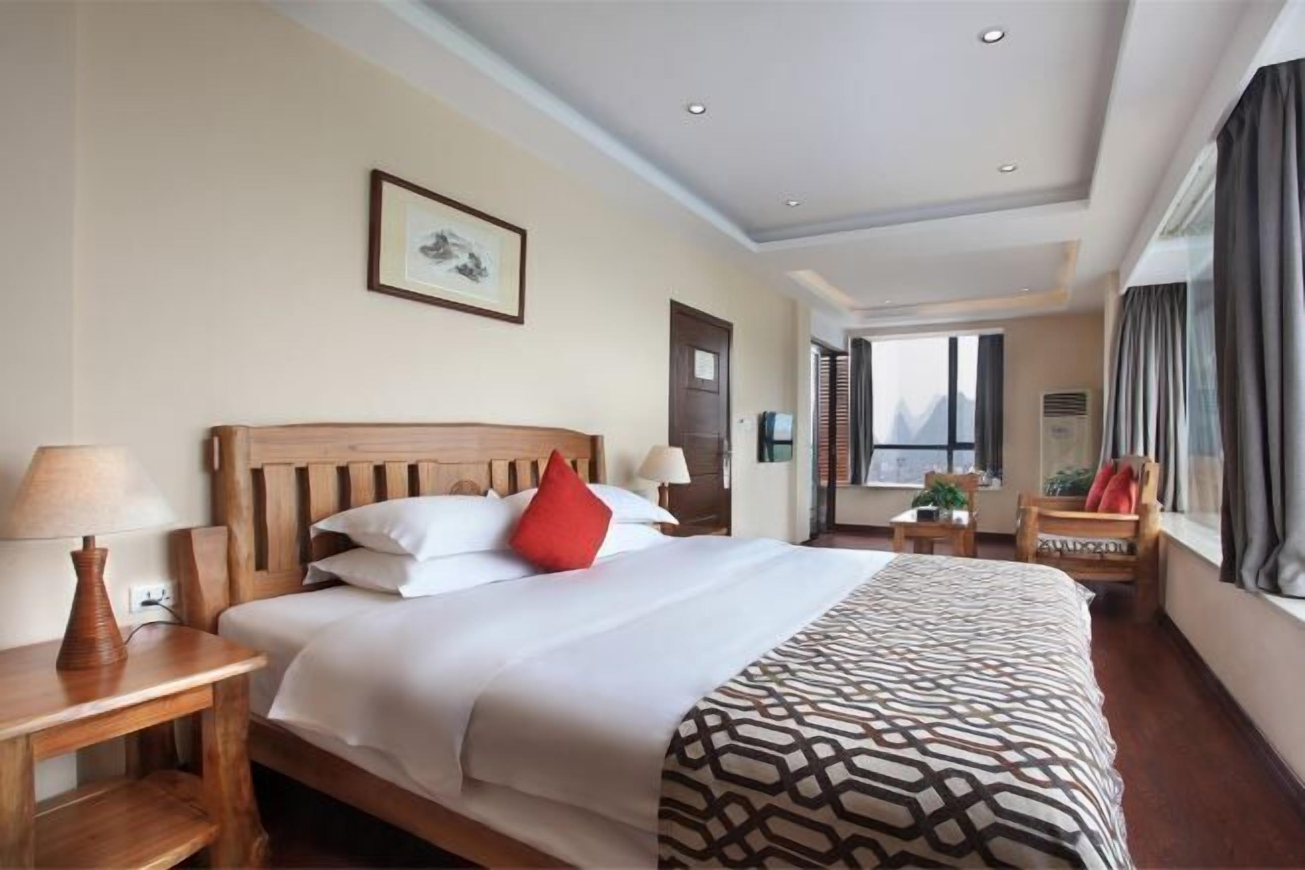 A hotel room with a large bed, bedside tables, a window, and a view.