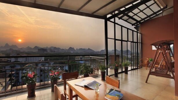 A balcony with a table, chairs, and potted plants. - Jinfeng Hotel (Guilin)