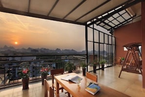 A balcony with a table, chairs, and potted plants. - Jinfeng Hotel (Guilin)