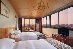A hotel room with two beds, a TV, a wooden ceiling, and a large window with a city view. - Jinfeng Hotel (Guilin)