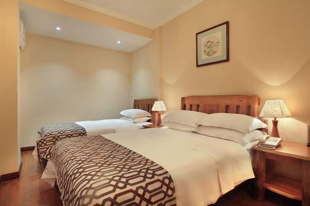 A hotel room with two beds, a wooden headboard, bedside lamps, a framed picture on the wall, and a wooden nightstand.