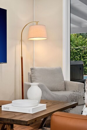 Ein modernes Wohnzimmer mit einem grauen Sofa, einer weißen Vase, einem Buch mit dem Titel 'Artful Lifestyle' und einer Stehlampe mit einem beige farbenen Lampenschirm.