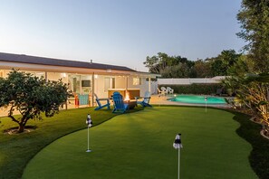 Ein Haus mit Swimmingpool, einem gepflegten Rasen und einer Feuerstelle.