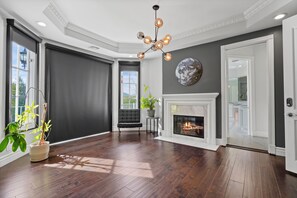 Ein geräumiges Zimmer mit Kamin, großem Fenster und einer Deckenleuchte.