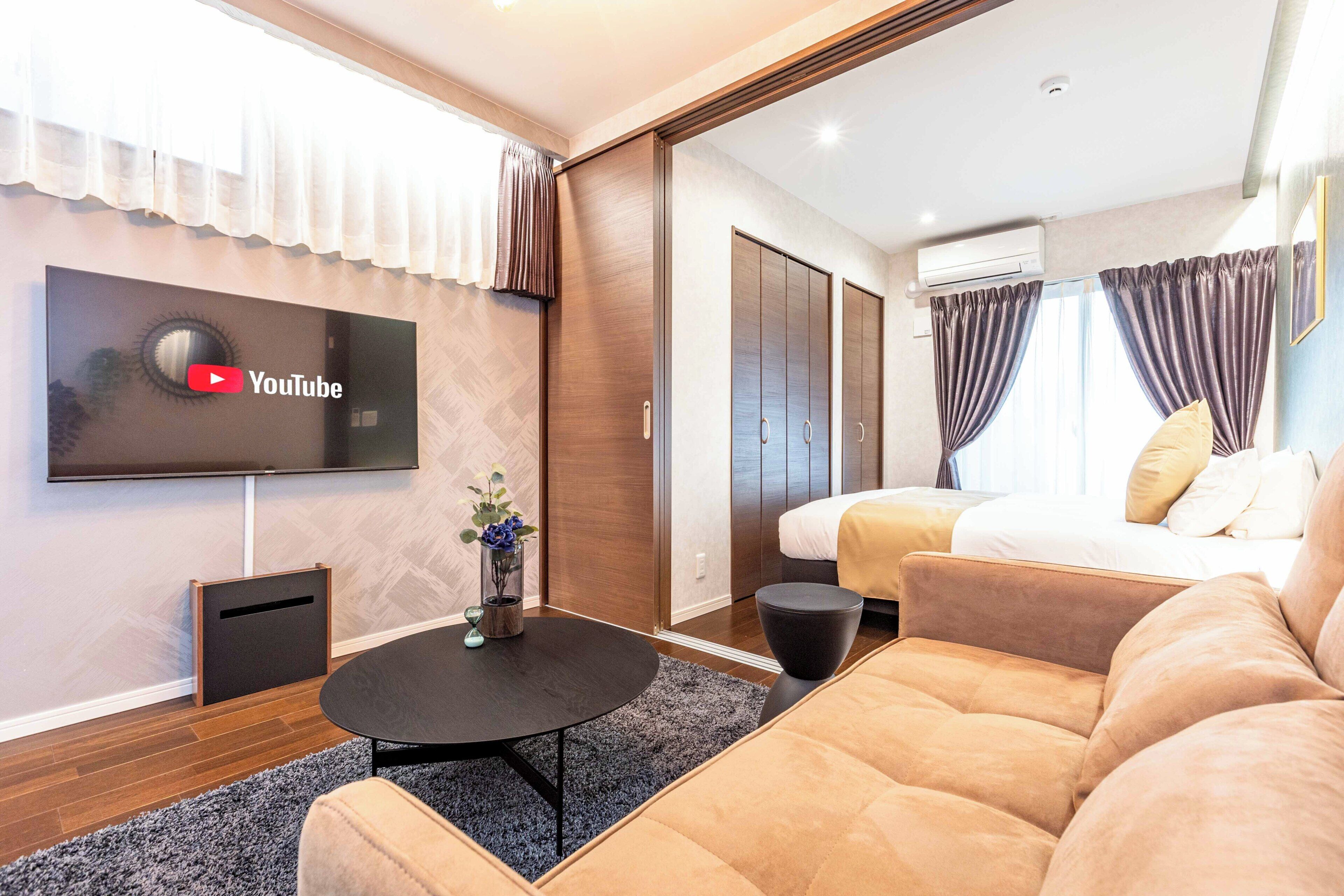 Una habitación de hotel moderna con una televisión de pantalla plana, un sofá, una mesa de centro y una cama.