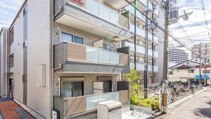 A multi-story residential building with balconies, a visible entrance, and a bike parking area. - FDS Panache (OSAKA/NISHINARIKU/HANAZONOMINAMI)