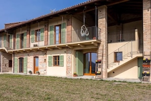 Una casa de dos pisos con balcón, escaleras y una puerta.