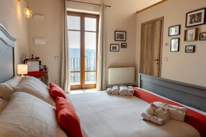A hotel room with a bed, a desk with a lamp, a window with a view, and a door. - Be Langhe in Monforte (Monforte d'Alba)