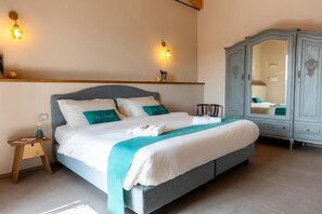 Una cama bien hecha con almohadas, una mesita de noche con lámpara y un armario con espejo.