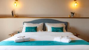 A neatly made bed with two pillows, a teal bedspread, and a towel on the side. - Be Langhe in Monforte (Monforte d'Alba)