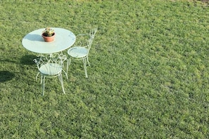A round table with two chairs and a potted plant on a grassy lawn.