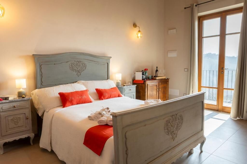 Un dormitorio con cama, mesitas de noche, cómoda y vistas a través de un ventanal.