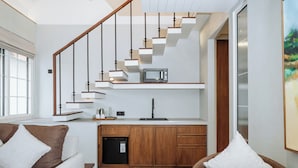 A modern kitchen with a built-in microwave, wooden cabinets, and a dining area with a wooden table and chairs. - Nuho Living (Pecatu)