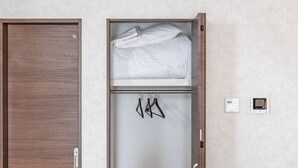 A hotel room with a wooden wardrobe, a bed with white bedding, and a wall-mounted thermostat. - FDS Luxe (OSAKA/NISHINARIKU/HANAZONOMINAMI)