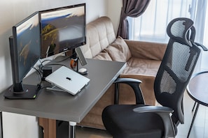 Ein moderner Arbeitsplatz mit zwei Bildschirmen, einem Laptop und einem schwarzen Bürostuhl.