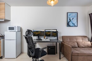 Eine moderne Küche mit Kühlschrank, Mikrowelle und einer Essecke mit Stuhl und Tisch.