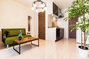 Ein modernes Wohnzimmer mit einem grünen Sofa, einem Holztisch und einem Blumentopf.
